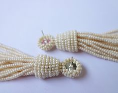 two pieces of white pearls are attached to the ends of ear pins on a white surface