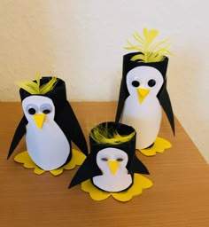 three paper penguins with yellow feathers on them