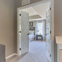 an open door leading to a bedroom with a bed in the corner and a dresser on the other side