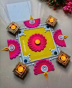 an artistically decorated diya with candles on the floor in front of some flowers