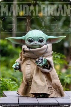 the baby yoda doll is posed on a skateboard in front of some bushes