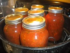 there are many jars with different kinds of sauces in them on the stove top