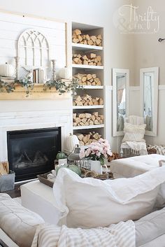 a living room filled with white furniture and lots of wood stacked on top of each other