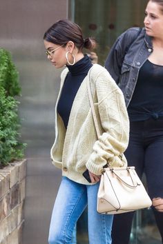 a woman walking down the street carrying a purse