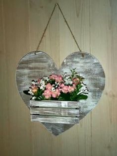 a wooden heart hanging on a wall with flowers in it