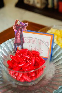 a bowl filled with red candy sitting on top of a table next to a sign