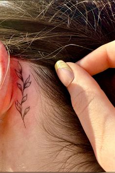 a woman's ear has a small tattoo on it