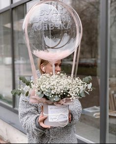 a woman holding a bouquet of flowers in front of a building