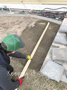 a young boy is working on some kind of project in the yard while wearing a green hat