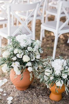 two vases filled with white flowers sitting next to each other on top of grass