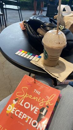 a book sitting on top of a table next to a coffee cup and an umbrella