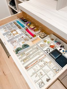 an open drawer filled with lots of different jewelry and bracelets on top of a wooden table