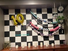 balloons and streamers are hanging on the wall in front of a checkered wall