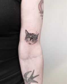 a woman with a cat tattoo on her arm and the other arm is holding a bird