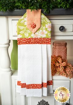 a kitchen towel hanging on the side of a white cabinet next to a potted plant