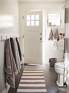 a bathroom with towels hanging on the wall and a toilet in the corner next to it