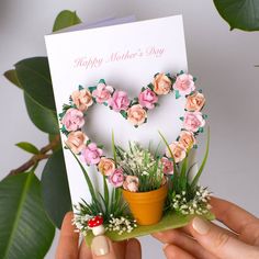 a hand holding a mothers day card with flowers in the shape of a heart