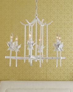 a white chandelier hanging from the ceiling in a room with yellow wallpaper