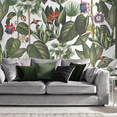 a living room with a couch and wallpaper that has tropical plants on the walls