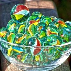 a glass bowl filled with colorful marbles on top of a wooden table