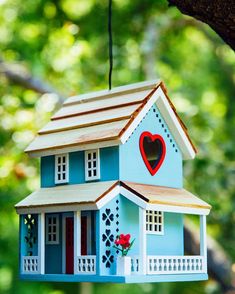 a blue birdhouse with a heart hanging from it's roof