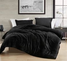 a bed with black comforter and pillows in a room