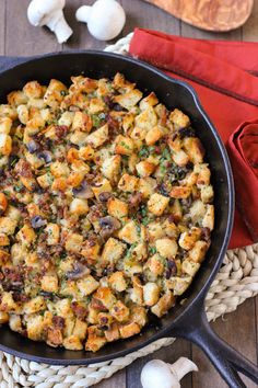 a pan filled with stuffing sitting on top of a table next to garlic and red napkins