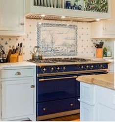 a blue stove top oven sitting inside of a kitchen next to white cabinets and counter tops