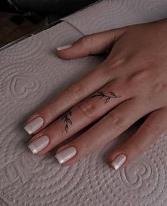 a woman's hand with a small flower tattoo on her left thumb and finger