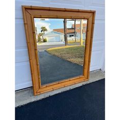 a large mirror sitting on the side of a garage door next to a driveway and palm trees