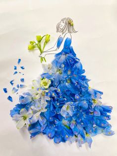 a dress made out of blue flowers on a white surface with a drawing of a woman in the background