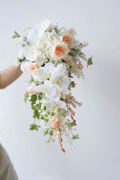 a woman holding a bouquet of white and peach flowers