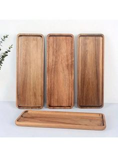 three wooden trays sitting next to each other on a white surface with flowers in the background