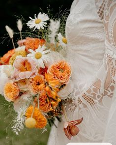 a bridal holding a bouquet of orange and white flowers