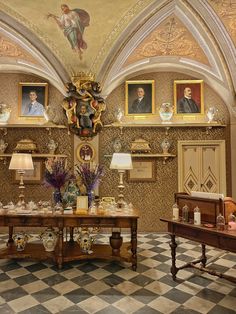 an ornately decorated room with paintings on the wall and two tables in front of them