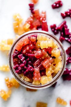 a jar filled with gummy bears sitting on top of a marble counter next to other candies