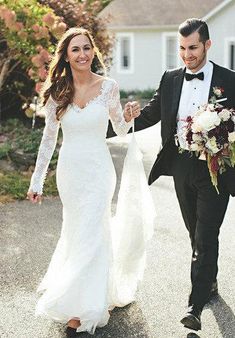 a bride and groom are walking down the street holding each other's hand as they hold hands