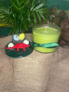 a green candle sitting on top of a table next to a bowl and potted plant