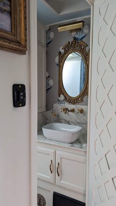 a bathroom sink sitting under a mirror next to a wall mounted toilet paper dispenser