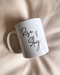 a white coffee mug with the words rise and slay written in black on it