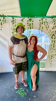 a man and woman dressed up in costume standing next to each other under a tent