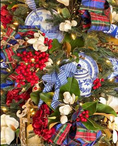 a christmas tree decorated with blue and white plates, holly wreaths and red berries