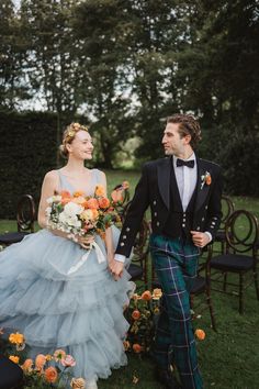 a man and woman in kilts holding hands walking down the aisle at their wedding