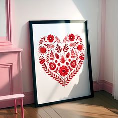 a heart - shaped painting is displayed on the floor next to a pink chair