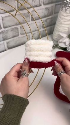 a woman is holding a piece of cake with white frosting and red ribbon on it