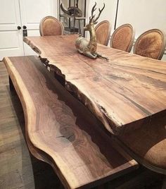 a wooden table with chairs around it and deer heads on the top, in front of a white door