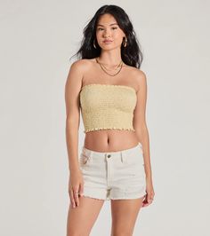 a woman in white shorts and a yellow top is posing for the camera with her hands on her hips