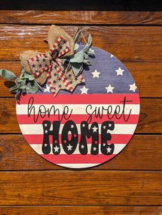 a wooden sign that says home sweet home with an american flag and bows on it