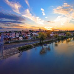 the sun is setting over a river with boats in it