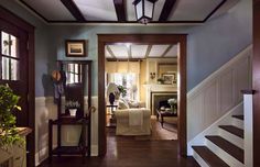 a living room with blue walls and wood floors is seen from the entry way to the dining area